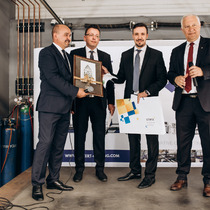 four mans stand at the platform with awards